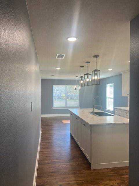 kitchen featuring a center island with sink, white cabinetry, and dark wood-type flooring