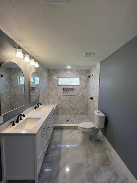 bathroom featuring tiled shower, vanity, and toilet