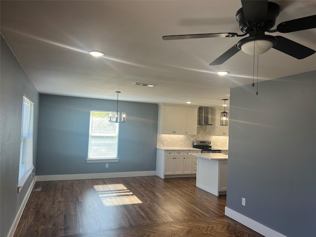 kitchen with stainless steel electric stove, white cabinetry, wall chimney exhaust hood, and decorative light fixtures