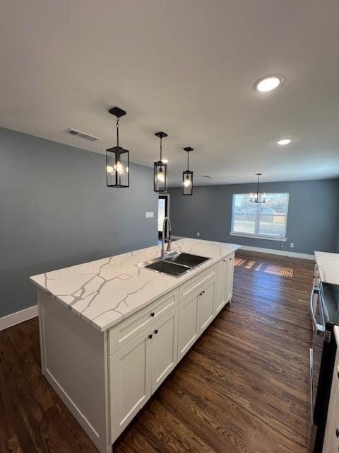 kitchen with a center island with sink, dark hardwood / wood-style floors, white cabinetry, and sink