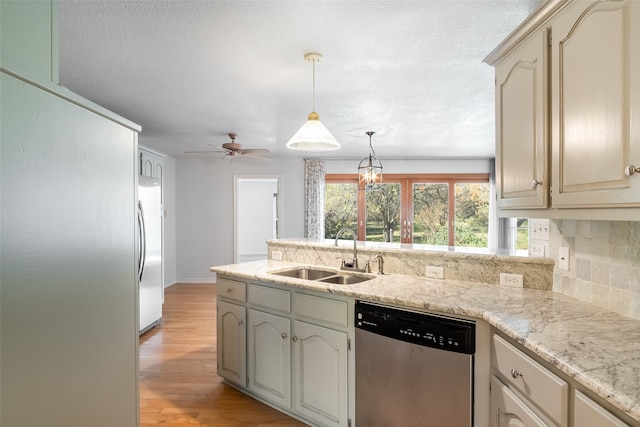 kitchen featuring stainless steel appliances, ceiling fan, sink, cream cabinets, and light hardwood / wood-style flooring