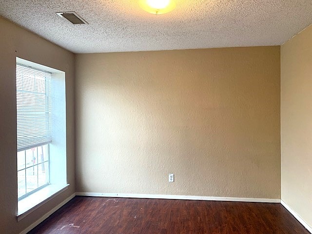 spare room featuring dark hardwood / wood-style flooring and a textured ceiling