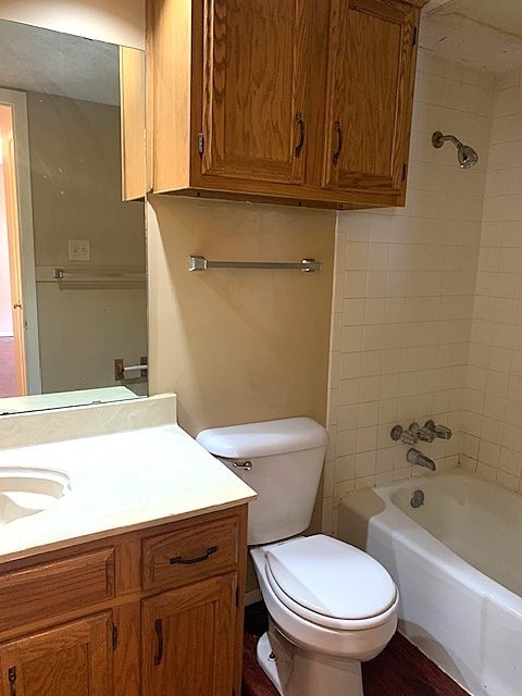 full bathroom with vanity, tiled shower / bath combo, and toilet