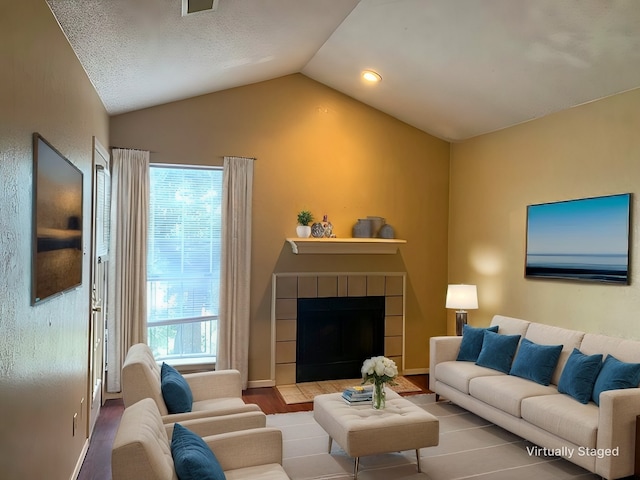 living room with lofted ceiling, a fireplace, wood-type flooring, and a healthy amount of sunlight