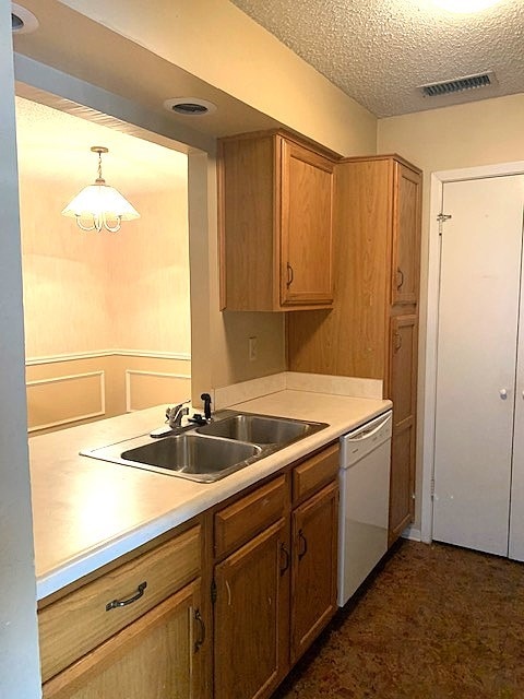 kitchen with pendant lighting, white dishwasher, sink, and a textured ceiling