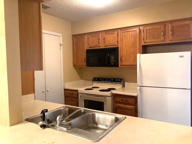 kitchen featuring white appliances, sink, and a textured ceiling