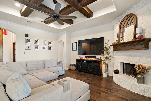 living room with a stone fireplace, dark hardwood / wood-style flooring, coffered ceiling, ceiling fan, and beam ceiling