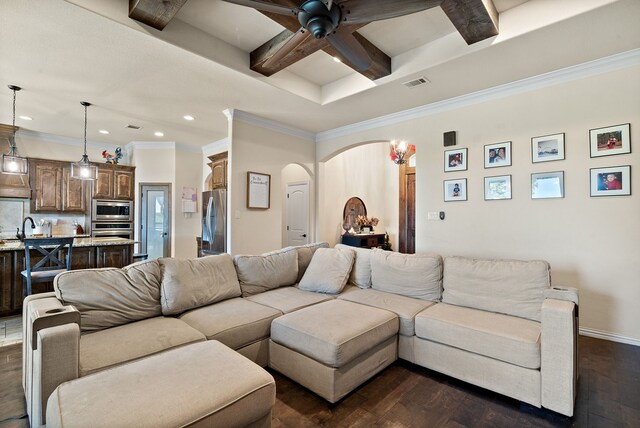 living room with ornamental molding, dark hardwood / wood-style flooring, sink, beamed ceiling, and ceiling fan