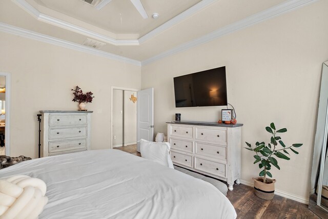 bedroom featuring ornamental molding, dark wood-type flooring, a tray ceiling, and ceiling fan