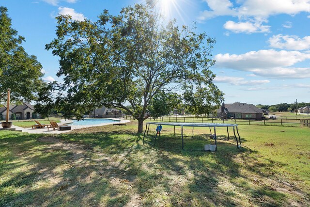 view of yard with a rural view, a fire pit, a fenced in pool, and a patio area