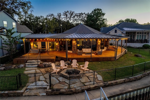 back house at dusk with an outdoor living space with a fire pit, a patio area, a yard, and a wooden deck