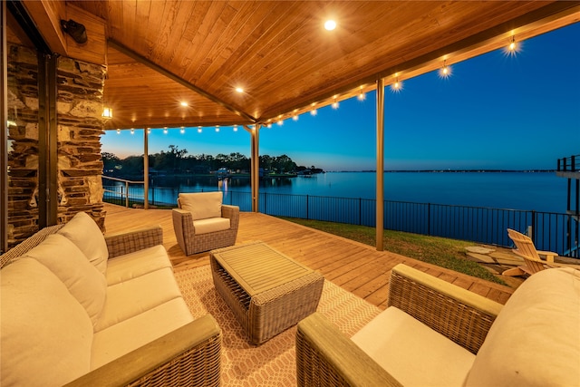 patio terrace at dusk with outdoor lounge area and a water view