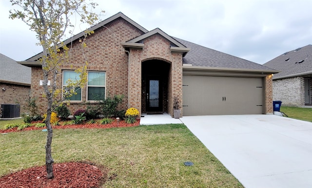 view of front of home featuring a front lawn, central AC unit, and a garage