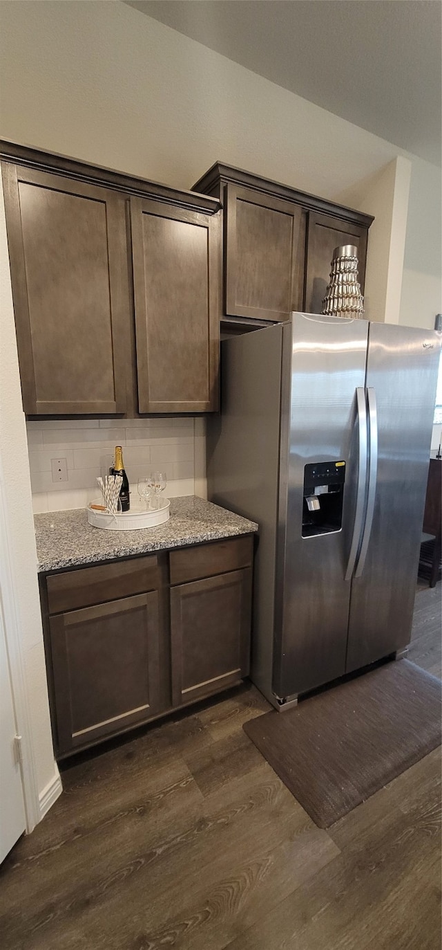 kitchen featuring light stone counters, dark brown cabinetry, stainless steel fridge with ice dispenser, and dark hardwood / wood-style flooring