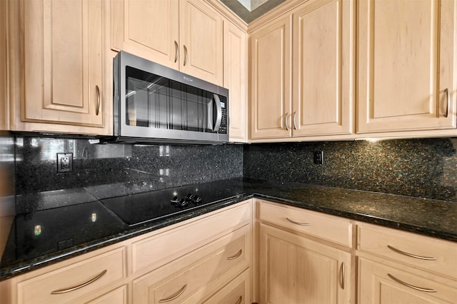 kitchen with light brown cabinetry, stainless steel microwave, black electric cooktop, and decorative backsplash