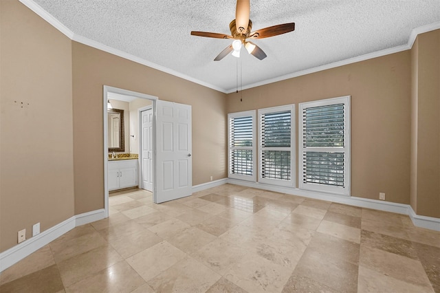 spare room featuring a textured ceiling, ornamental molding, a ceiling fan, and baseboards