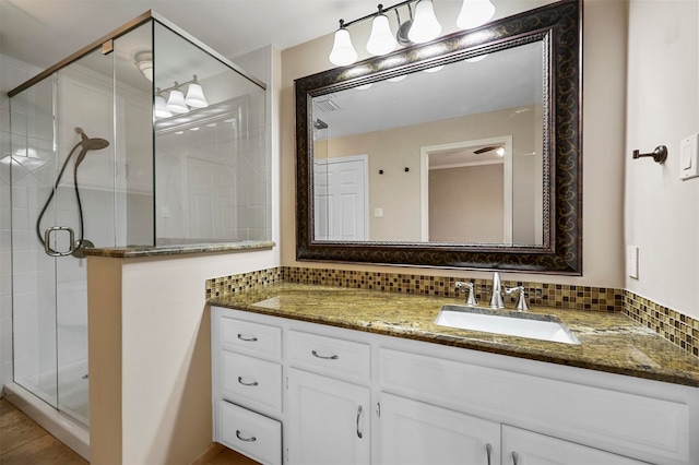 bathroom with a shower stall, decorative backsplash, and vanity