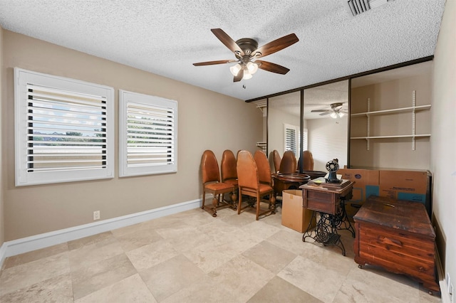 office area featuring baseboards, visible vents, ceiling fan, and a textured ceiling