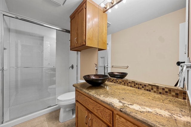 bathroom with toilet, vanity, tile patterned floors, tasteful backsplash, and a stall shower