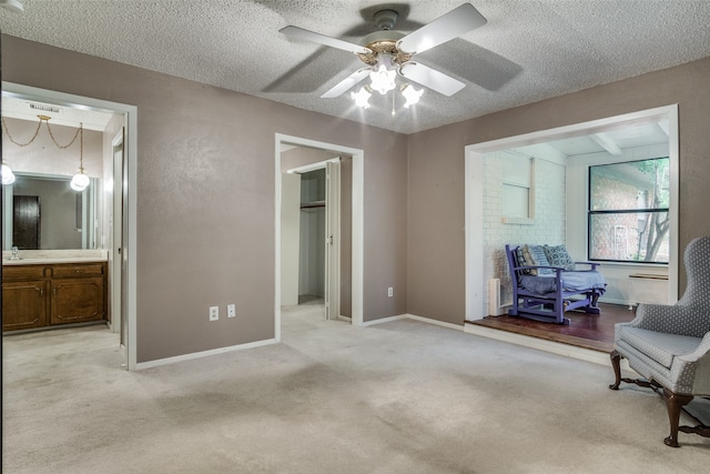 living area featuring light carpet, a textured ceiling, sink, and ceiling fan