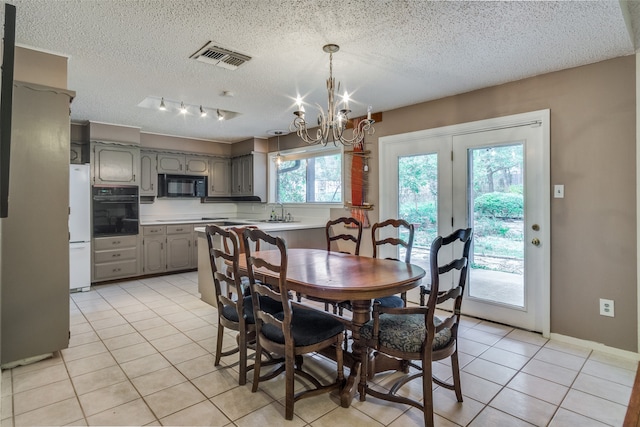 tiled dining space featuring sink, a chandelier, and a textured ceiling