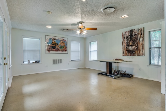 unfurnished living room with ceiling fan and a textured ceiling