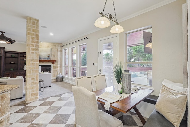 dining area with crown molding, a fireplace, and decorative columns