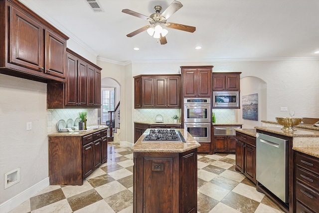 kitchen with ornamental molding, a center island, stainless steel appliances, and backsplash