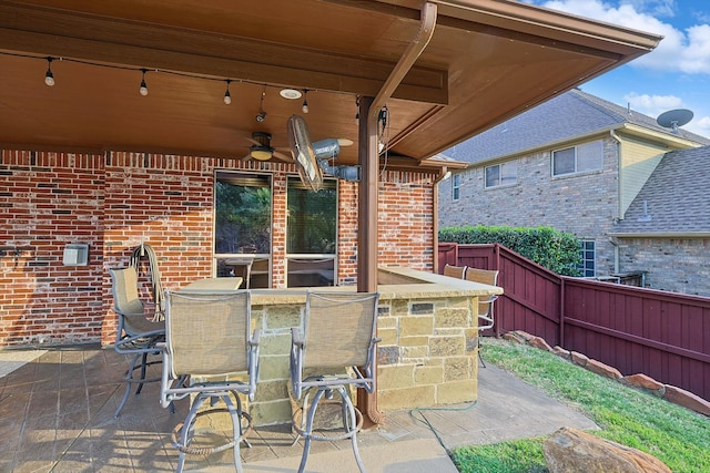 view of patio with ceiling fan and a bar