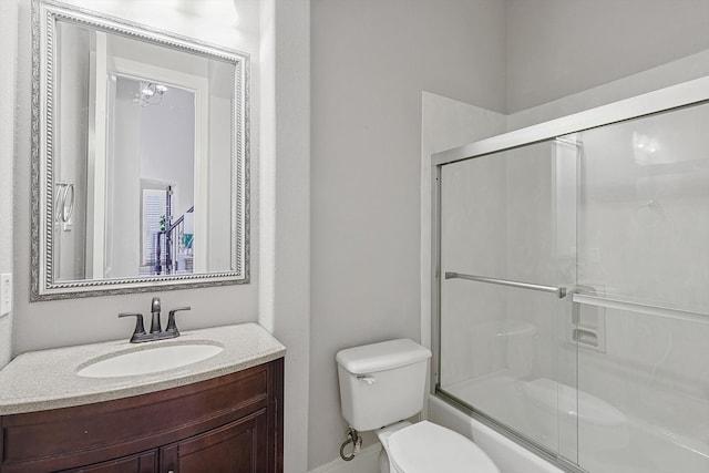 full bathroom featuring vanity, combined bath / shower with glass door, and toilet