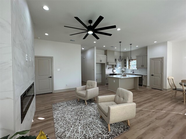 living room with ceiling fan, light hardwood / wood-style flooring, and a fireplace