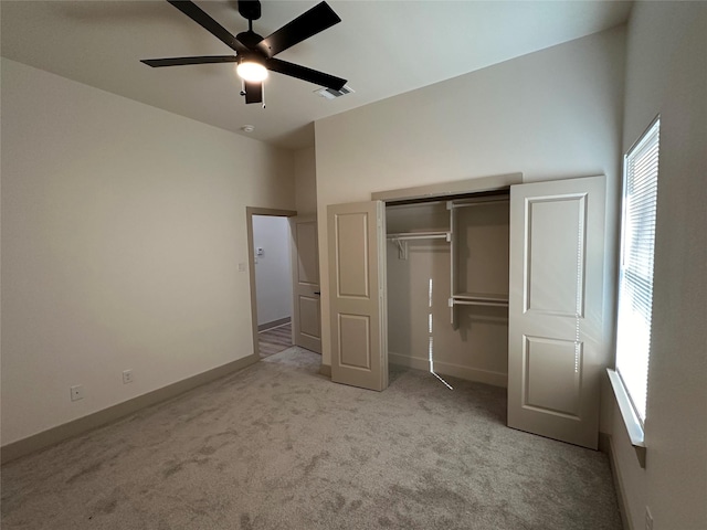 unfurnished bedroom featuring light carpet, a closet, ceiling fan, and a high ceiling