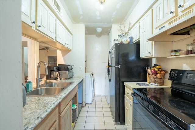 kitchen featuring light tile patterned floors, light stone countertops, black appliances, washing machine and dryer, and sink