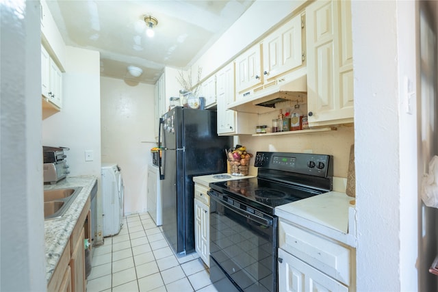 kitchen with washer and dryer, black appliances, sink, white cabinetry, and light tile patterned floors