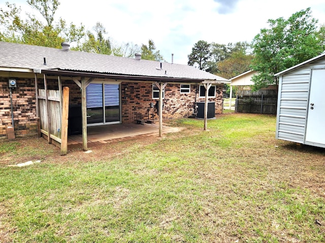 rear view of property with a shed, a patio, and a lawn