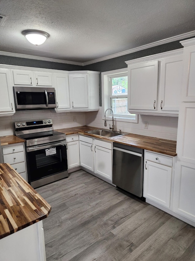 kitchen featuring sink, butcher block countertops, stainless steel appliances, and white cabinetry