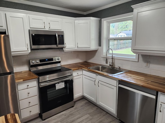 kitchen featuring appliances with stainless steel finishes, white cabinetry, butcher block counters, and sink