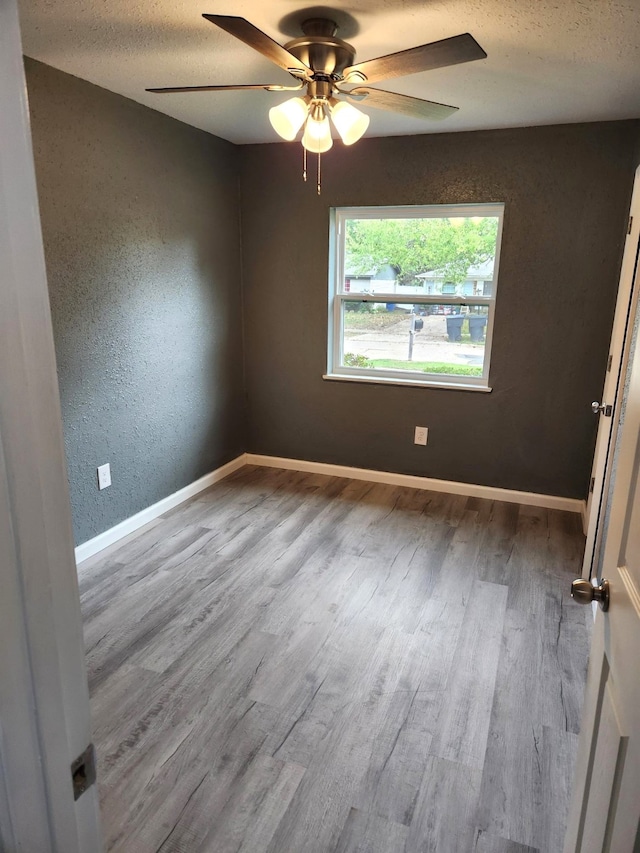 empty room with light hardwood / wood-style flooring, a textured ceiling, and ceiling fan