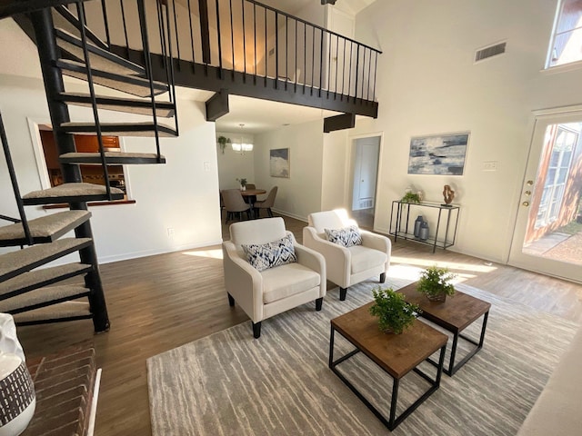 living room with wood-type flooring, a towering ceiling, and an inviting chandelier