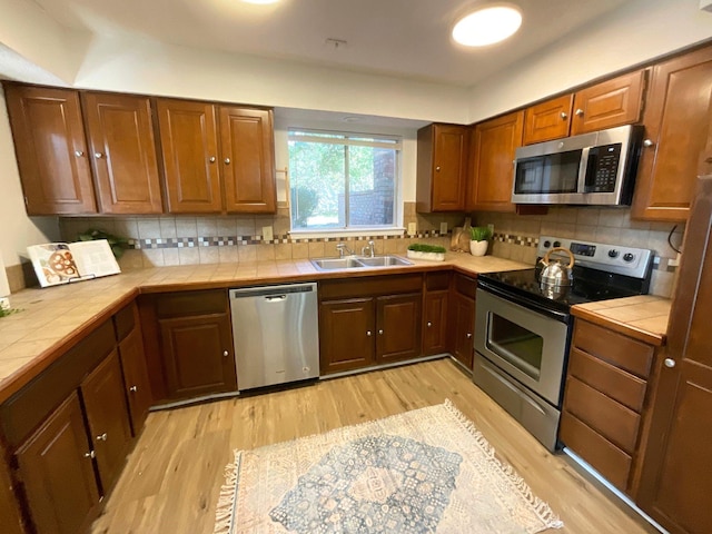 kitchen featuring tile countertops, decorative backsplash, sink, and stainless steel appliances