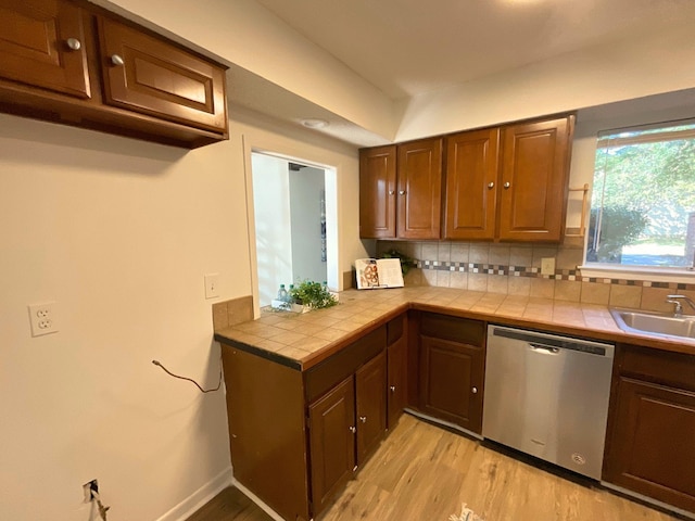 kitchen with tile counters, dishwasher, sink, tasteful backsplash, and light hardwood / wood-style flooring