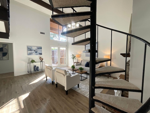 stairway featuring hardwood / wood-style floors and high vaulted ceiling