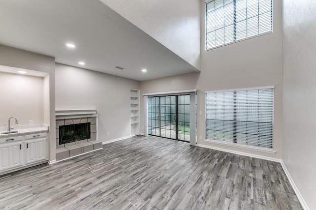 unfurnished living room with plenty of natural light, light wood-type flooring, sink, and a tile fireplace