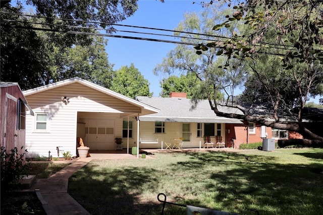 rear view of house with central AC, a yard, a garage, and covered porch