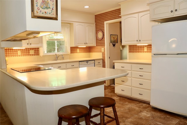 kitchen with a kitchen breakfast bar, white cabinets, and white appliances