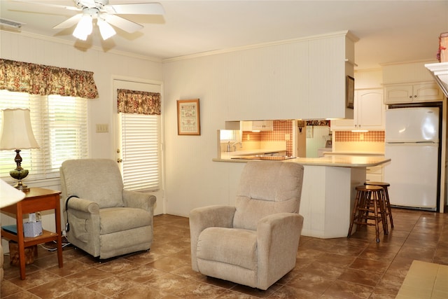 living area featuring ceiling fan and ornamental molding