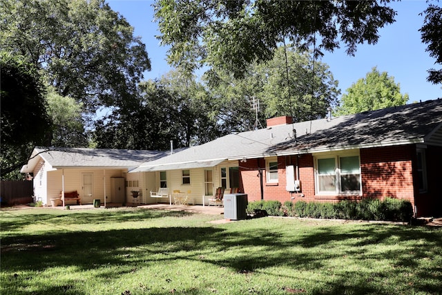 rear view of property featuring central air condition unit and a lawn