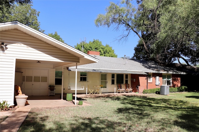 rear view of house with a yard, covered porch, central AC, and a garage