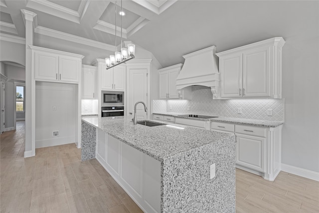 kitchen featuring sink, white cabinetry, stainless steel appliances, light stone counters, and premium range hood