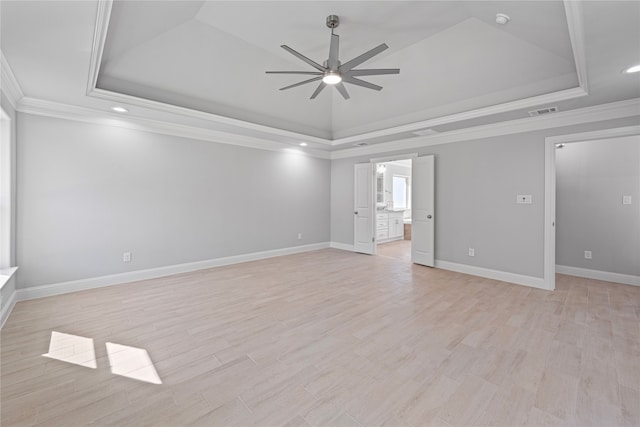 empty room featuring ceiling fan, crown molding, a tray ceiling, and light wood-type flooring